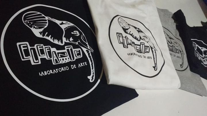 Poleras negras, blancas y grises con el logo de Elefante, laboratorio de arte