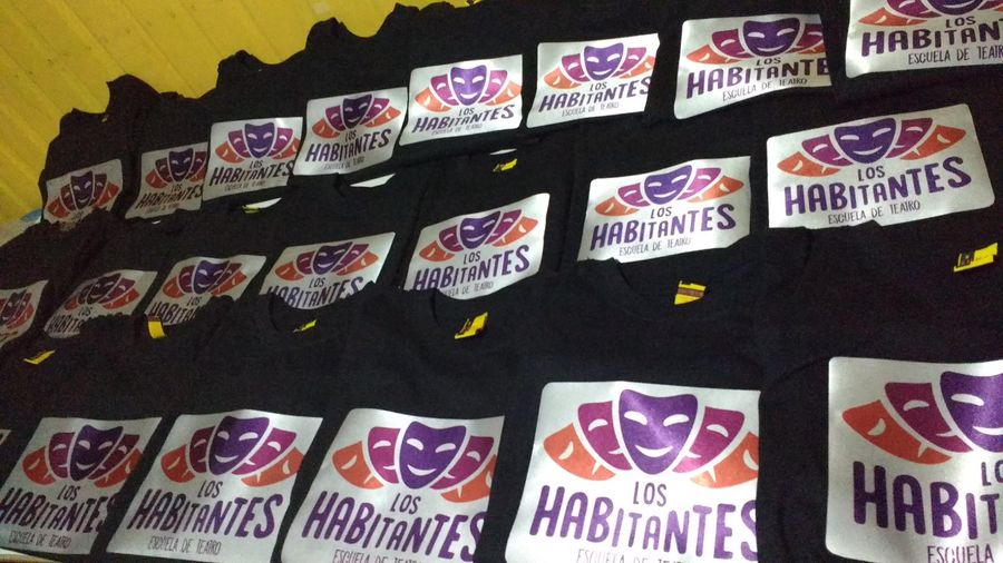 Poleras negras con el logo de la Escuela de Teatro Los Habitantes