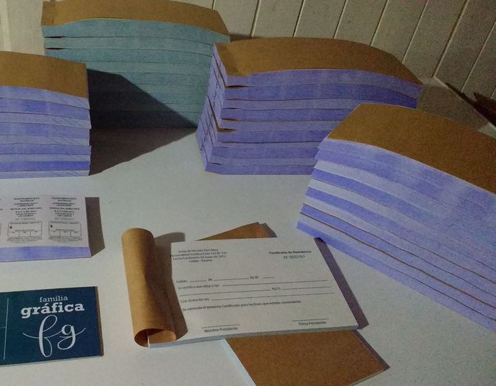 Talonarios con tapa kraft apilados y un certificado de residencia abierto