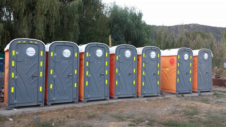 Fila de baños químicos con el logo de Qui-masol en vinilo y franjas reflectantes